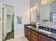 Bathroom featuring double sinks with dark granite countertops, wood cabinets, and a walk-in closet at 2227 Chestnut Cir, Erie, CO 80516