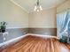 Inviting dining room features hardwood flooring, elegant chandelier, wainscotting and natural light from a large window at 2227 Chestnut Cir, Erie, CO 80516