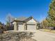 Lovely home featuring a three-car garage, stone accents, and a spacious driveway surrounded by mature trees on a sunny day at 2227 Chestnut Cir, Erie, CO 80516