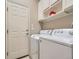 Laundry room with white washer and dryer, overhead cabinets, and a nearby exterior door at 2227 Chestnut Cir, Erie, CO 80516