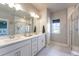 Bright bathroom featuring double vanity, quartz counters, tile flooring, and glass enclosed shower at 21574 E 59Th Dr, Aurora, CO 80019