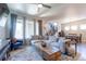 Bright living room featuring a plush sectional sofa, decorative rug, and modern ceiling fan at 21574 E 59Th Dr, Aurora, CO 80019