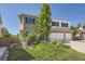 Landscaped front yard of the two-story brick home with a three-car garage and a view of mature trees at 2950 Wyecliff Ln, Highlands Ranch, CO 80126
