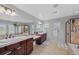 Beautiful bathroom with dual sinks, lots of mirrors, granite counters, and tiled shower at 12015 Blackwell Way, Parker, CO 80138