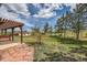 Landscaped backyard with a pergola, mature trees, and a charming view of the barn on the property at 6646 S Fundy Ct, Centennial, CO 80016