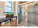 Modern bathroom boasts a glass-enclosed shower and stylish wood vanity with decorative plants and rolled towels at 6646 S Fundy Ct, Centennial, CO 80016