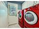 Well-organized laundry room featuring a vibrant red washer and dryer set, as well as ample storage at 6646 S Fundy Ct, Centennial, CO 80016
