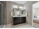 A well-lit bathroom boasting a double sink vanity, large mirrors, and a tiled shower at 806 Peony Ct, Brighton, CO 80601