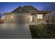 Charming home's front exterior featuring a three-car garage and a covered porch at twilight at 806 Peony Ct, Brighton, CO 80601
