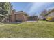 Spacious backyard with lush lawn, covered patio, and charming brick exterior at 32 Eagle Dr, Littleton, CO 80123