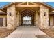 Beautiful stone building entrance with wooden beams and view of a lake and wrought iron gate at 32 Eagle Dr, Littleton, CO 80123