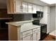 Kitchen with white cabinets, a black stovetop, and a view into the living area with a stone fireplace at 18193 E Kentucky Ave # 201, Aurora, CO 80017