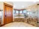 Bright bathroom featuring a soaking tub, glass enclosed shower, and tan tile at 6928 S Eaton St, Littleton, CO 80128