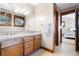 Bathroom featuring double sinks, wood cabinets, tile floors and view into Bedroom at 6928 S Eaton St, Littleton, CO 80128