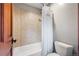 Bathroom featuring shower/tub combination with tan tile and a white toilet at 6928 S Eaton St, Littleton, CO 80128