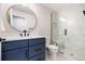 Modern bathroom featuring a walk-in shower, a round mirror, and a stylish vanity with sleek fixtures at 6928 S Eaton St, Littleton, CO 80128