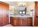 Bathroom with wood cabinets, granite counters, large mirror, and decorative chandelier at 6928 S Eaton St, Littleton, CO 80128