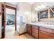 Bathroom featuring double sinks, wood cabinets, tile floors and view into bedroom at 6928 S Eaton St, Littleton, CO 80128