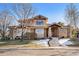 Two-story stucco home featuring stone accents, covered porch, mature trees and concrete steps at 6928 S Eaton St, Littleton, CO 80128