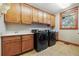 Functional laundry room with wood cabinets, sink and modern black washer and dryer at 6928 S Eaton St, Littleton, CO 80128