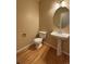 A clean powder room featuring a pedestal sink and wood floors at 10027 Sylvestor Rd, Highlands Ranch, CO 80129