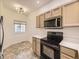 Compact kitchen featuring neutral cabinets and modern appliances, plenty of counter space and a window view at 12265 E 2Nd Dr, Aurora, CO 80011