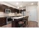 Modern kitchen with island, stainless steel appliances, and dark wood cabinets at 155 S Monaco Pkwy # 114, Denver, CO 80224