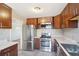 Well-lit kitchen with stainless steel appliances, wooden cabinets, and tile flooring at 3580 Locust St, Denver, CO 80207