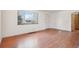Living room with hardwood floors, white walls, window, and white door at 3580 Locust St, Denver, CO 80207