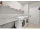 Well-organized laundry room with modern washer and dryer, ample counter space, and extra storage shelves at 13445 Kearney St, Thornton, CO 80602