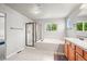 Bright bathroom featuring a glass-enclosed shower, soaking tub, vanity and tiled floors at 13445 Kearney St, Thornton, CO 80602