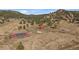 Aerial view of a tennis court and pond on the property, surrounded by mature trees at 7082 Silverhorn Dr, Evergreen, CO 80439