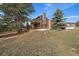 Two-story home with a private deck and a large yard with mature trees in the distance at 7082 Silverhorn Dr, Evergreen, CO 80439