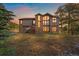 Beautiful exterior at sunset featuring a stone chimney, large windows, solar panels, and a stairway leading to the side entrance at 7082 Silverhorn Dr, Evergreen, CO 80439