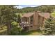 Two-story home featuring a balcony with outdoor seating amidst lush greenery at 7082 Silverhorn Dr, Evergreen, CO 80439