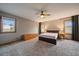 Bedroom with neutral walls, carpet, ceiling fan, bedside lamps, and views of the surrounding land at 7082 Silverhorn Dr, Evergreen, CO 80439