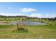 Pond with dock is surrounded by grassy meadow and trees under a sunny sky at 7082 Silverhorn Dr, Evergreen, CO 80439