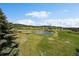 Expansive view of a private pond surrounded by trees and lush greenery, highlighting the property's serenity at 7082 Silverhorn Dr, Evergreen, CO 80439