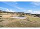 Scenic view of a peaceful pond surrounded by trees and grass, offering a serene escape at 7082 Silverhorn Dr, Evergreen, CO 80439