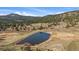 Aerial view of the property pond surrounded by lush green landscape with a mountain backdrop at 7082 Silverhorn Dr, Evergreen, CO 80439