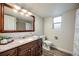 Bright bathroom with granite countertops, wood cabinets, and a framed mirror at 14867 E Pacific Pl, Aurora, CO 80014