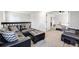 Spacious living room featuring a black leather sofa and ottoman leading into the bedroom at 14867 E Pacific Pl, Aurora, CO 80014