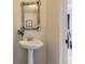 Charming powder room with pedestal sink, rustic mirror, and views of the adjacent dining area at 7822 South Kittredge Circle, Englewood, CO 80112
