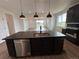 A well-lit kitchen featuring an island with a sink, dark cabinetry, and hardwood floors at 2141 S Irvington St, Aurora, CO 80018