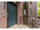 A close-up of the front door showing brick detail, a dark teal door, and wrought iron railing at 2950 E 17Th Ave, Denver, CO 80206