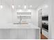 Bright kitchen with marble waterfall island, stainless appliances, white cabinets, and wood floors at 2950 E 17Th Ave, Denver, CO 80206