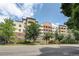A lovely street view of the multi-story condo with brick and painted siding and mature trees at 2200 S University Blvd # 212, Denver, CO 80210