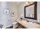 Cozy powder room features a decorative mirror, tile accents and wood vanity at 27732 Squaw Pass Rd, Evergreen, CO 80439