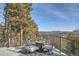 Deck with outdoor furniture and a fire pit, offering stunning views of the surrounding mountains and trees at 27732 Squaw Pass Rd, Evergreen, CO 80439