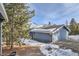 Exterior view of a blue house with snow on the roof, showcasing its cozy design and mountain setting at 27732 Squaw Pass Rd, Evergreen, CO 80439